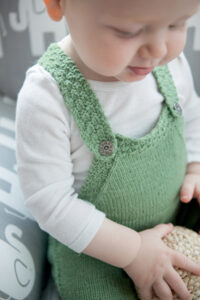 baby wearing knitted green overalls